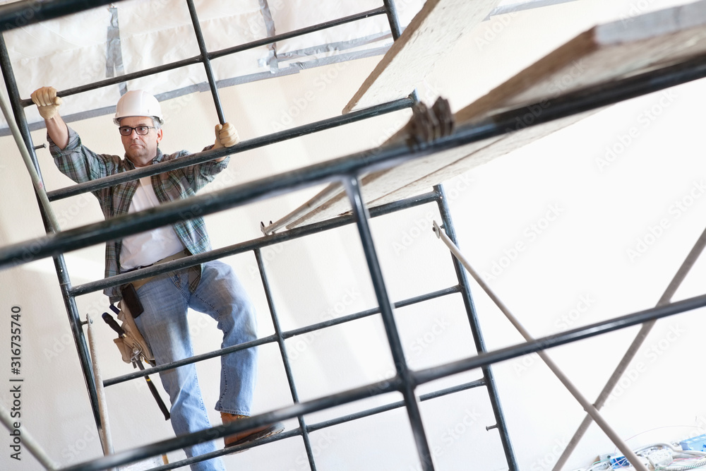 Construction worker climbing up the scaffold