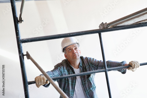 Construction worker standing near scaffolding while looking up