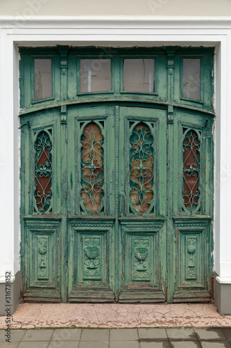 Retro vintage wooden door with metal and wood carvings on the european public building exterior.