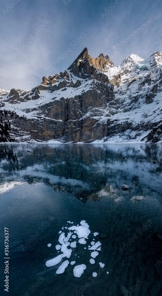 frozen bubbles on Lake Oeschinensee with reflection of the Blümlisalp Mountains in the Swiss Alps