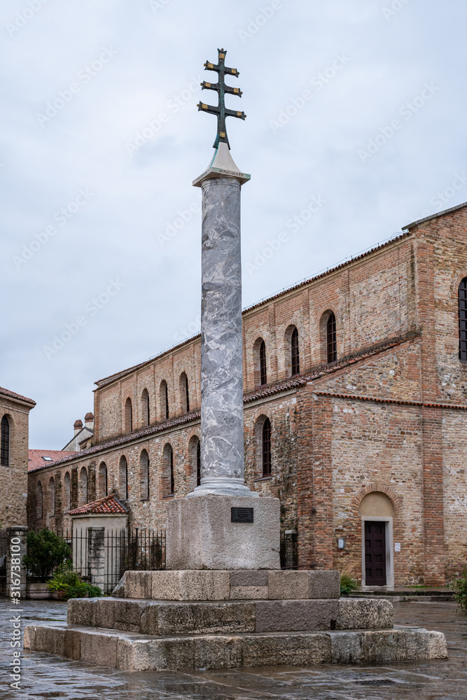 Pillar in front of the church of Grado after sunset in autumn