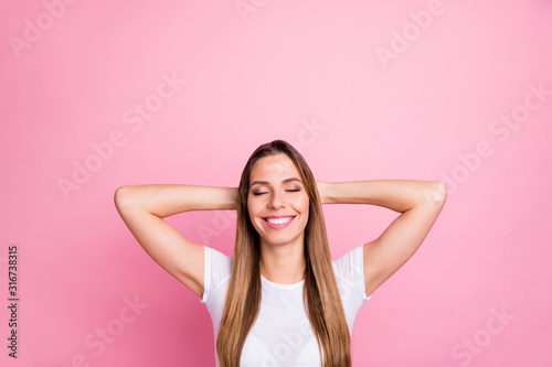 Photo of beautiful lady peaceful harmonic mood holding arms behind head eyes closed toothy dreamy smiling wear casual white t-shirt isolated pink color background