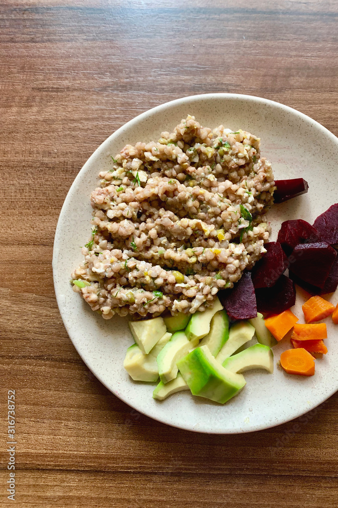 Healthy vegan buckwheat breakfast with mung bean, boiled vegetables and avocado