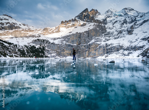 girl in winter outfit looking down on frozen lake Oeschinensee photo