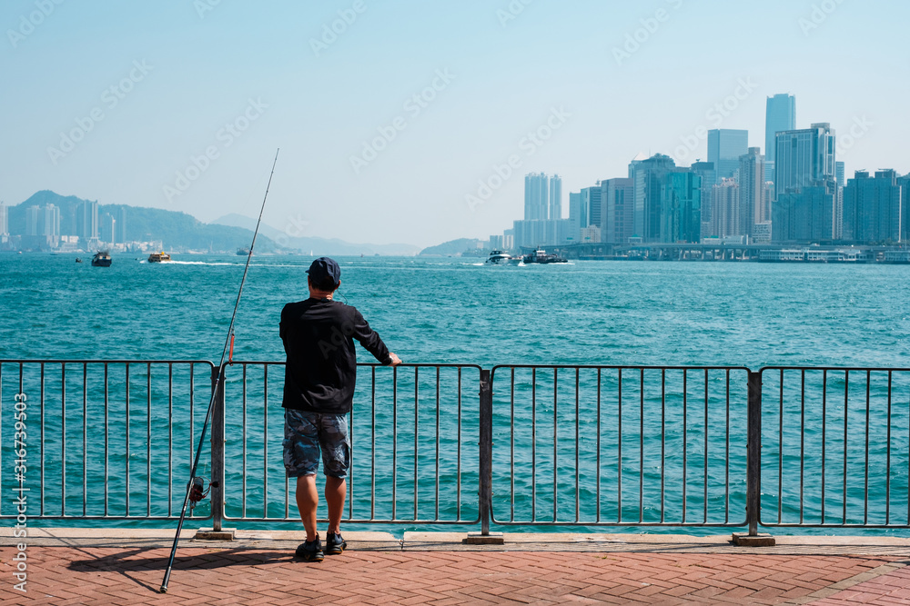 fisher man with fishing rod on coast with skyline background 