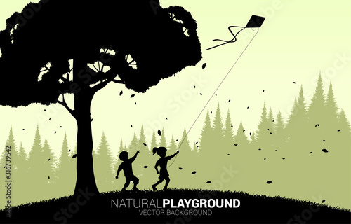 silhouette of boy and girl running with flying kite in the sky with big tree. Concept of children play and learn in natural.