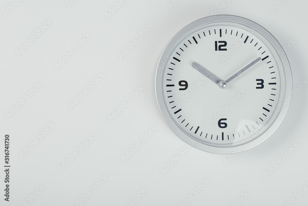 White wall clock with a yellow used hanging on the wall. Minimalist image of a wall clock on a light gray background with copy space White wall clock with a yellow used hanging on the wall. Minimalist image of a wall clock on a light gray background with copy space