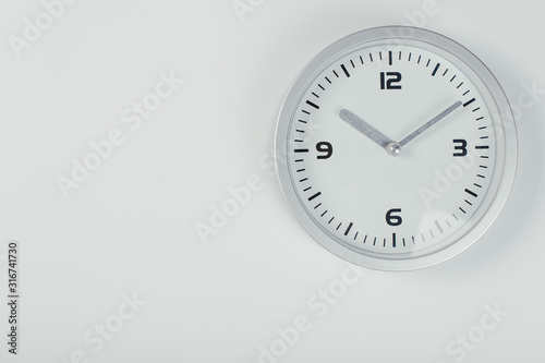 White wall clock with a yellow used hanging on the wall. Minimalist image of a wall clock on a light gray background with copy space