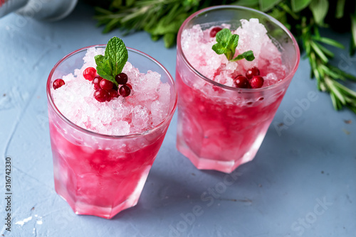 Two Glass of Cold Cocktail with Cranberry and Vodka Decorated with Mint and Ripe Cranberries Blue Background Summer Beverage