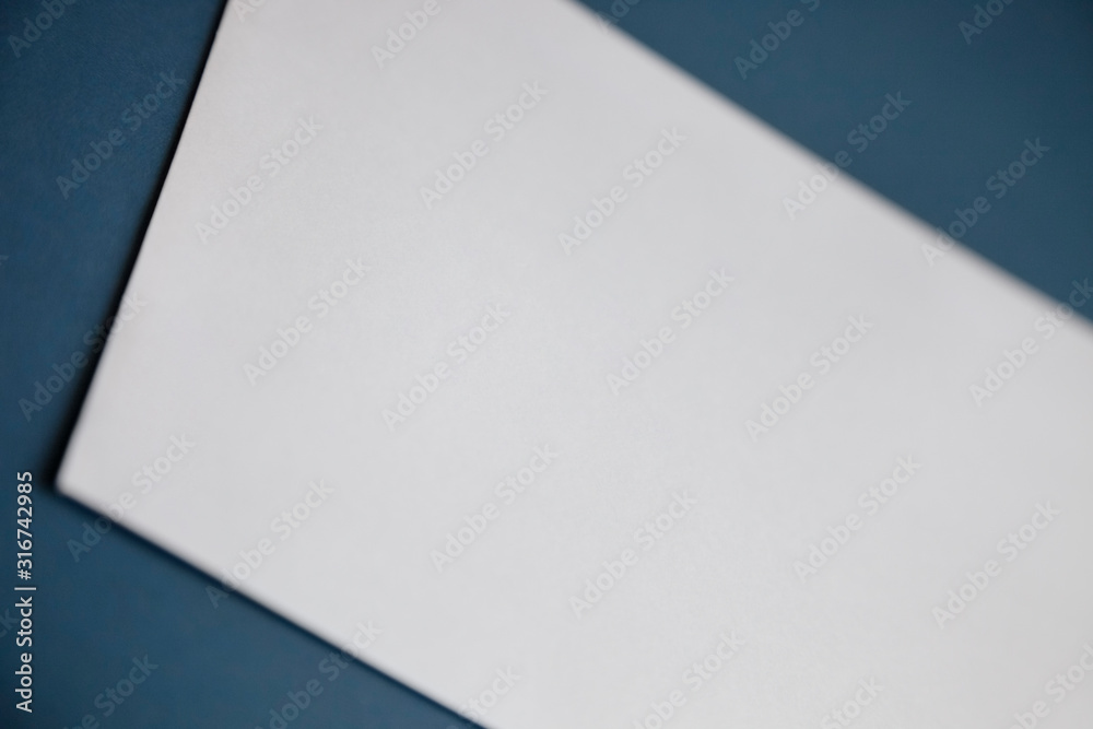 Cropped image of a blank white paper on dark blue surface Cropped image of a blank white paper on dark blue surface