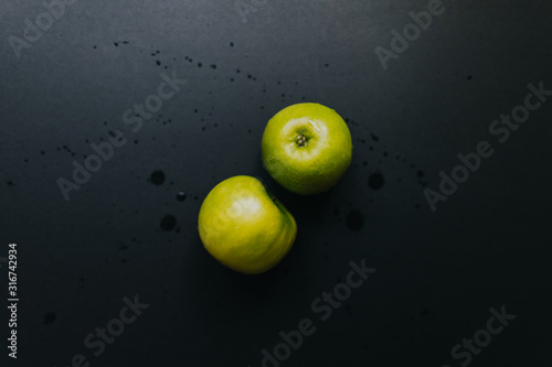 Green apple on black background with water drops, flat lay. © nikkimeel