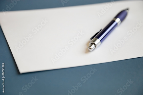 Metallic pen on a blank white paper over dark blue background