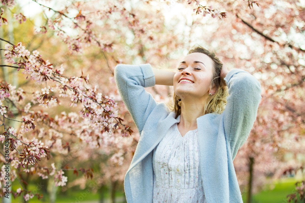Young woman enjoying the nature in spring. Dancing, running and whirling in beautiful park with cherry trees in bloom. Happiness concept Young woman enjoying the nature in spring. Dancing, running and whirling in beautiful park with cherry trees in bloom. Happiness concept