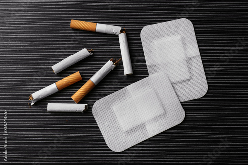 Nicotine patches and broken cigarettes on black table, flat lay photo