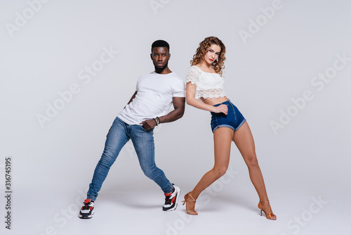 Couple dancers posing over white background. Man and woman are dancing, dance costumes. International dance group. Dancers dance. Passionate original variety of pair of dancers. Fitness concept