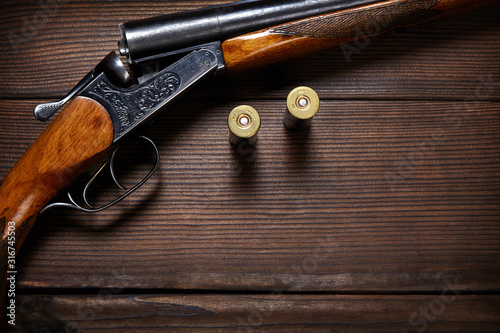 Vintage shotgun and cartridges on wooden background.
