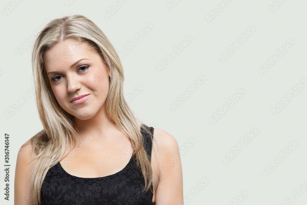 Portrait of young woman smiling over gray background Portrait of young woman smiling over gray background