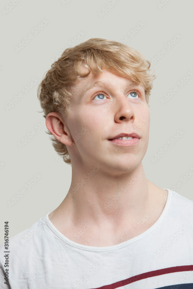 Contemplative young man standing against gray background Contemplative young man standing against gray background