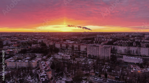 Beautiful pink sunset over the city. Smoke from the chimney on the horizon. © Ilya Nikanovich