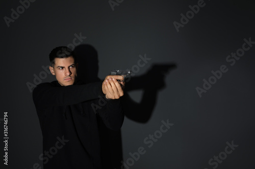 Professional killer with gun on black background