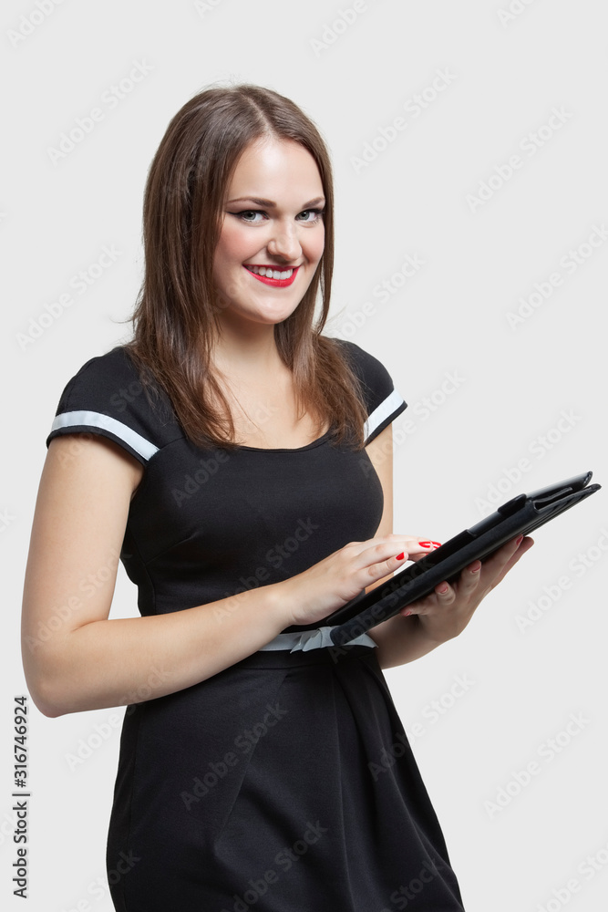 Portrait of young woman using tablet PC over gray background Portrait of young woman using tablet PC over gray background