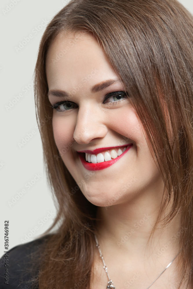 Close-up portrait of a beautiful woman with red lips smiling over gray background Close-up portrait of a beautiful woman with red lips smiling over gray background