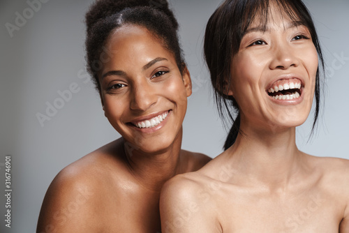 Two multiethnic young beautiful smiling topless women