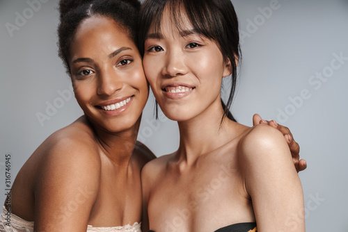 Two multiethnic young beautiful smiling topless women