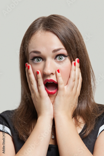 Close-up of shocked young woman with gray eyes and red lips