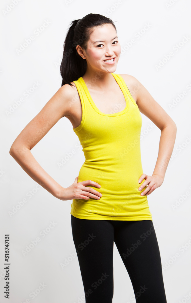Portrait of young woman smiling with hands on hips against white background Portrait of young woman smiling with hands on hips against white background