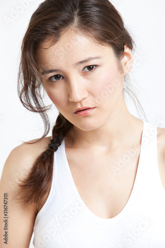 Portrait of beautiful Asian woman in white tank top against white background
