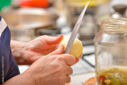 Cooking in the kitchen, peeling onions from the peel with a knife