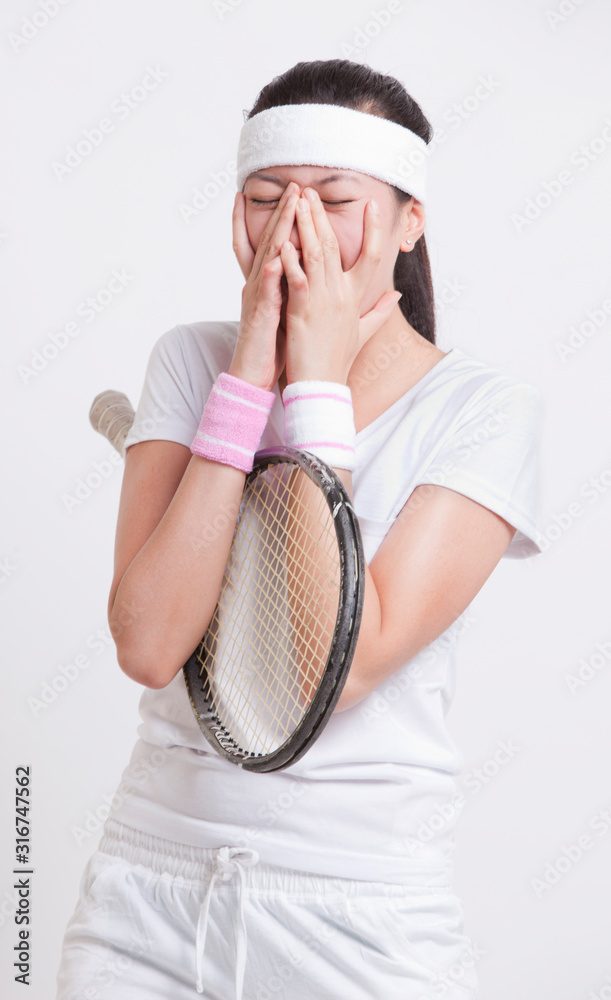 Young female tennis player with hands on face against white background Young female tennis player with hands on face against white background