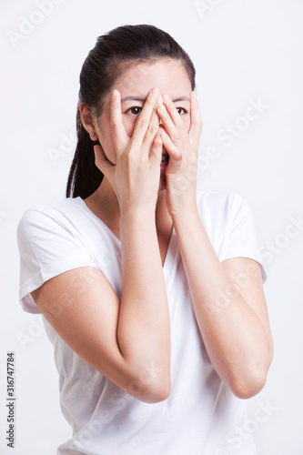 Frightened young woman with hands on face against white background