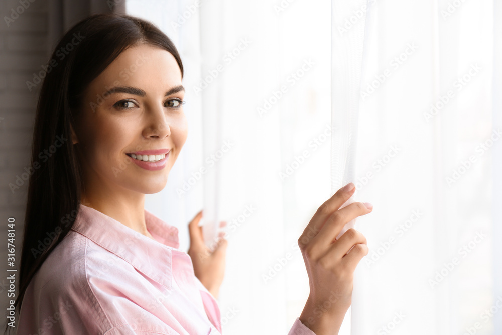 Woman opening window curtains at home in morning Woman opening window curtains at home in morning