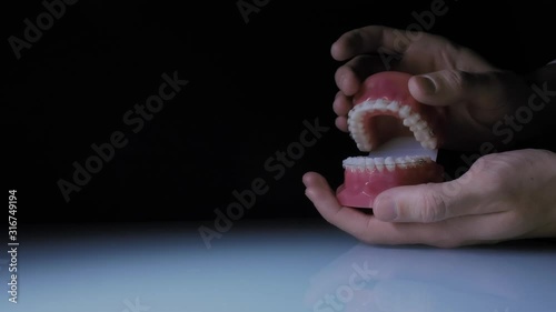 Close-up of teeth with transparent braces. Demonstration of the jaw with braces in the doctor's hand.