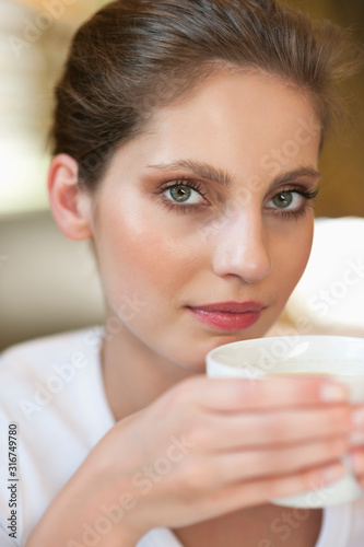 Close-up portrait of a young woman holding coffee cup