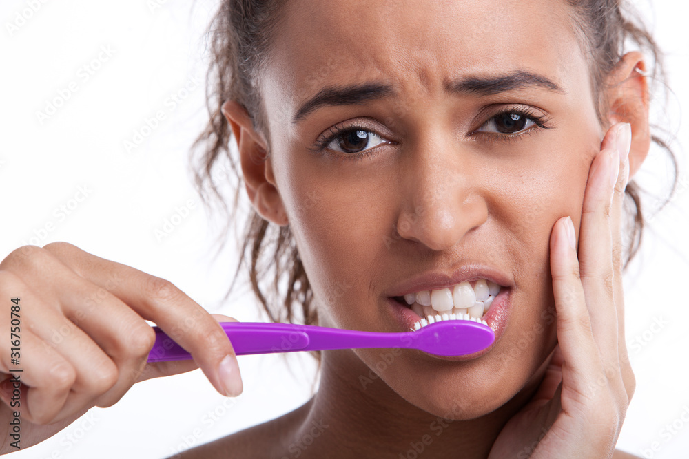 Young Mixed Race woman with toothbrush suffering from toothache against white background Young Mixed Race woman with toothbrush suffering from toothache against white background