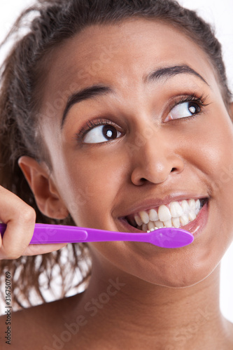 Young Mixed Race woman brushing teeth against white background
