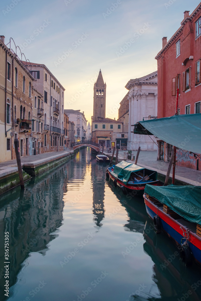 Fototapeta premium Canal with boats between the colorful houses at sunrise