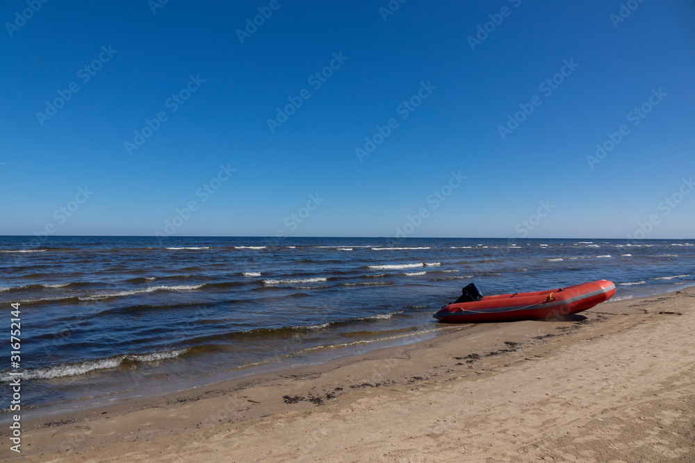 Rubber boat on a sand seashore on a blue sky background. Rubber boat on a sand seashore on a blue sky background.