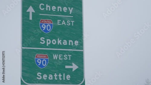 CLOSE UP: Traffic sign weathers a severe blizzard engulfing the state of Washington. Green highway traffic sign directs traffic around the state of Washington during a snowstorm. Extreme weather. photo