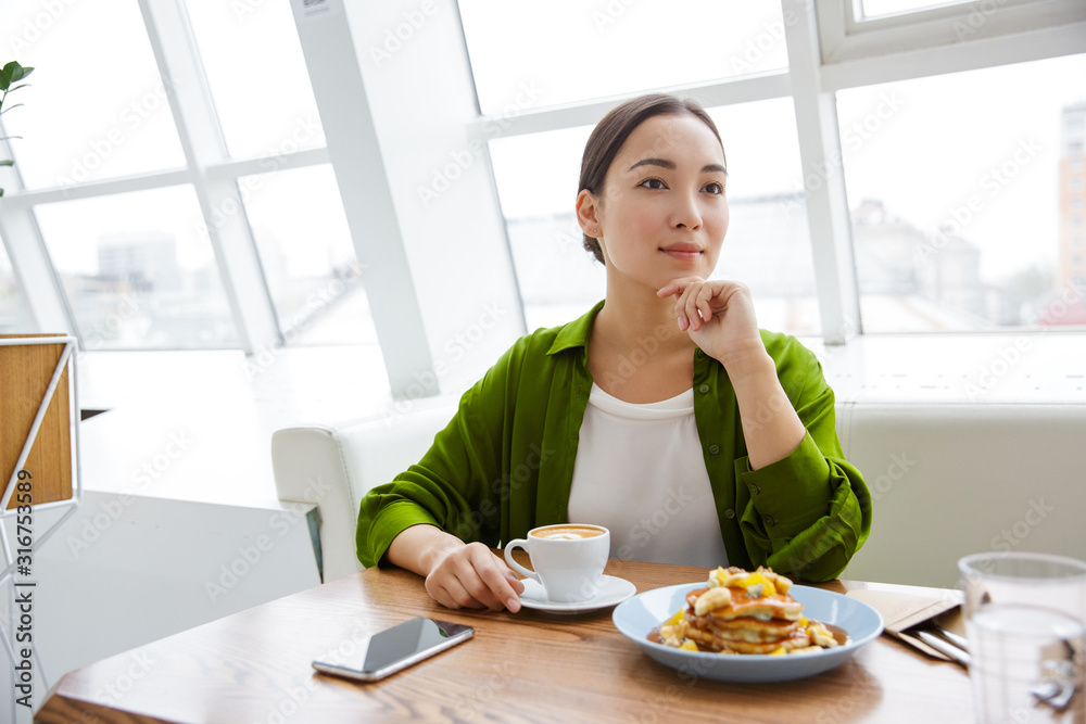 Smiling asian woman having pancakes for breakfast Smiling asian woman having pancakes for breakfast