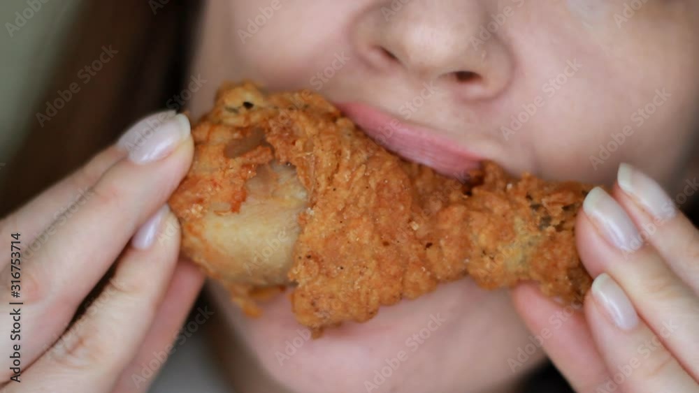 Hungry woman eating chicken. Mouth and food close-up. Fast food in female hands. Selective focus Hungry woman eating chicken. Mouth and food close-up. Fast food in female hands. Selective focus