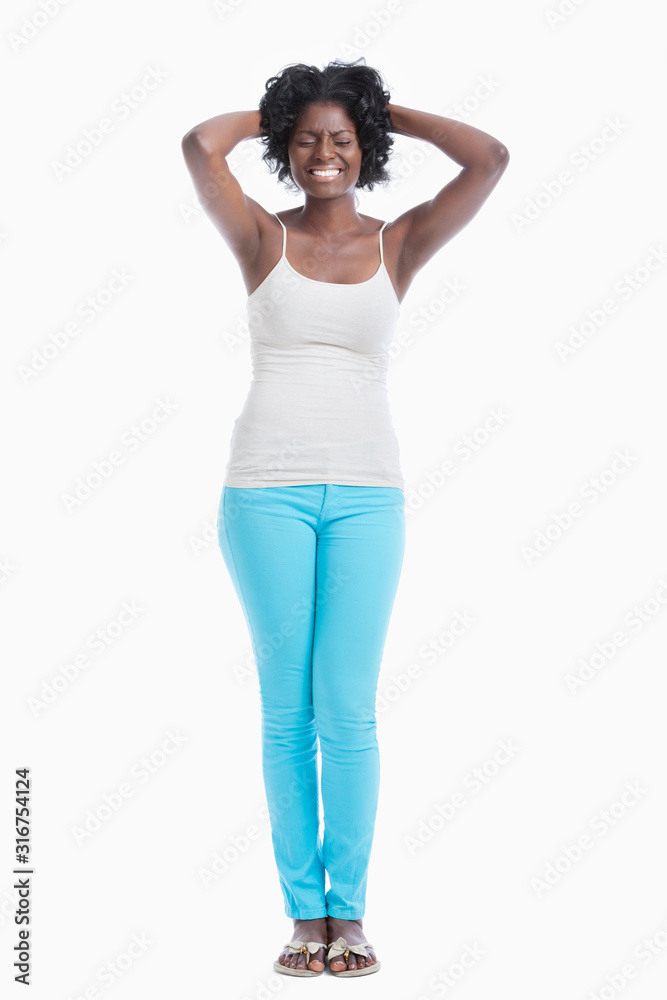 Frustrated young woman with hands behind head standing against white background Frustrated young woman with hands behind head standing against white background