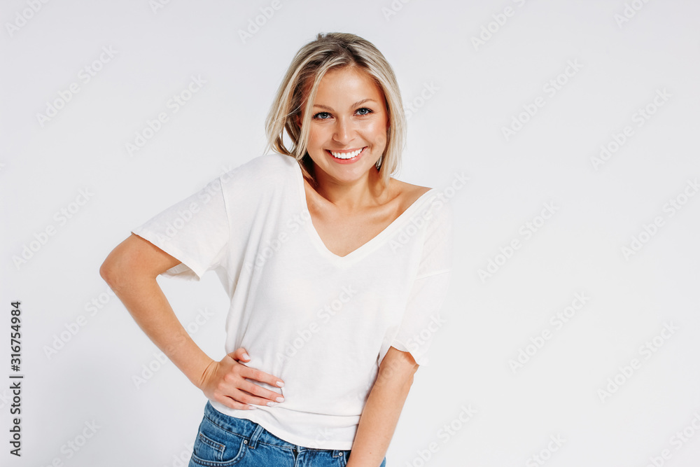 Charming friendly blonde smiling woman 35 year in white t-shirt and blue jeans looking at camera isolated on white background, mock up Charming friendly blonde smiling woman 35 year in white t-shirt and blue jeans looking at camera isolated on white background, mock up