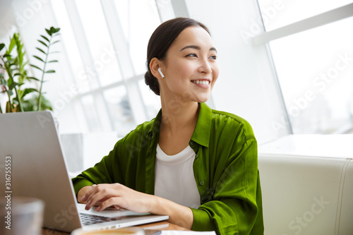 Obraz na plátně Smiling beautiful young asian woman working on laptop