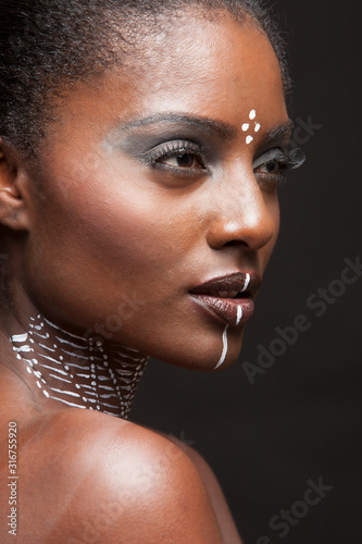 Portrait of young beautiful black woman posing with traditiional paint  photo