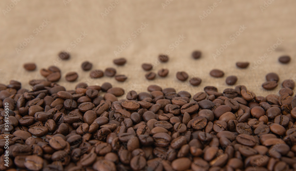 Freshly roasted coffee beans sprinkled with beans on burlap with copy space for text Freshly roasted coffee beans sprinkled with beans on burlap with copy space for text