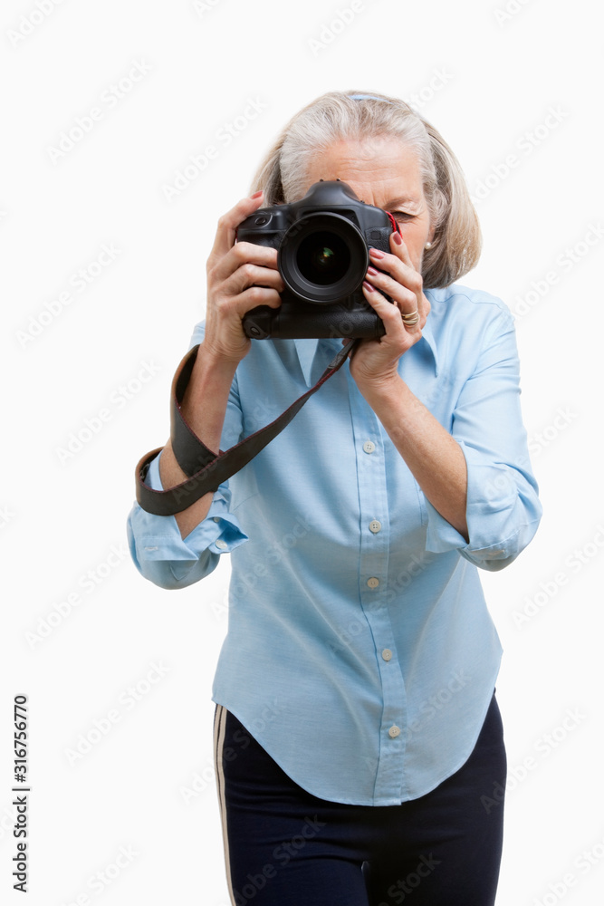 Senior female photographer using camera against white background Senior female photographer using camera against white background